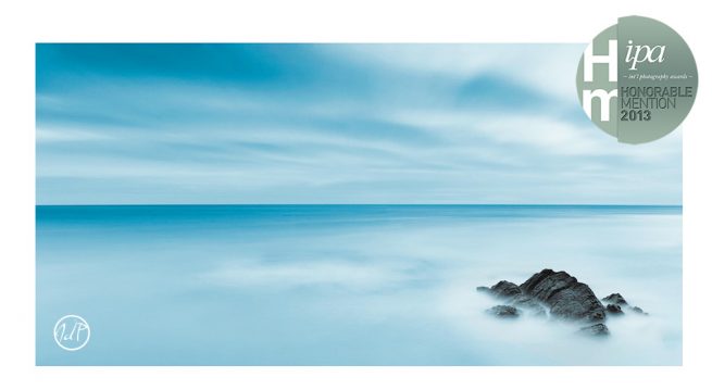Strong winds stir up the Irish sea to crash upon this lone rock as the clouds rush overhead in this 3 minute long exposure image. by John Dunne. 