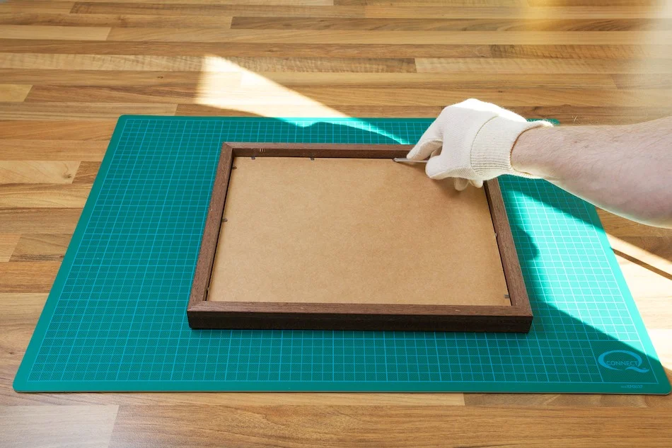 An image showing the brads being bent to secure the print in the frame from John Dunne Photography by John Dunne.